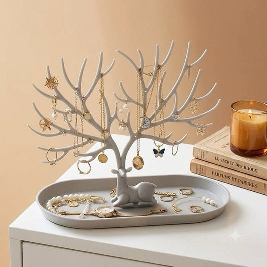 arbre à bijoux gris sur commode livres et bougie