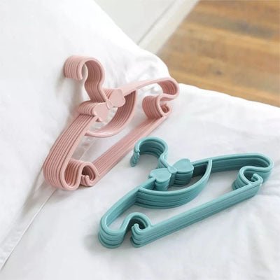 cintre enfant bleu et rose posés sur le lit